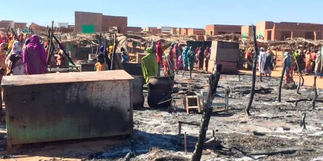 Residents of a refugee camp gather around the burned remains of makeshift structures, in Genena, Sudan.   (Organization for the General Coordination of Camps for Displaced and Refugees / AP)