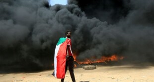 A man  stands in front of a burning pile of tyres during anti-coup protest  in Khartoum, October 21, 2021.  Photo by Reuters/Mohamed Nureldin Abdallah