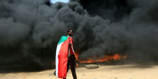 A man  stands in front of a burning pile of tyres during anti-coup protest  in Khartoum, October 21, 2021.  Photo by Reuters/Mohamed Nureldin Abdallah