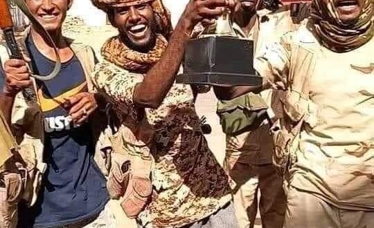 RSF soldiers holding a trophy belonging to Almerikh football club after raiding the club premises